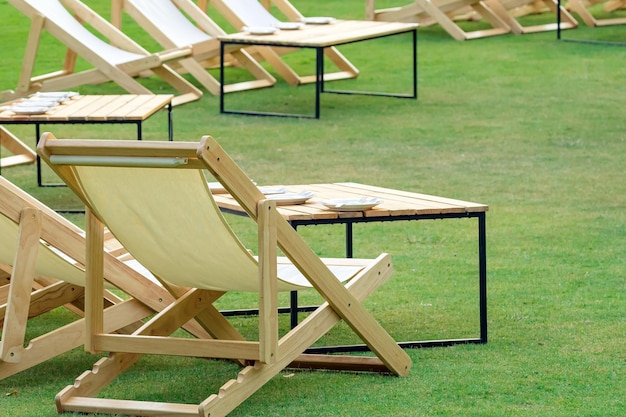 Many white deck chairs with tables for dinner in lawn is surrounded by shady green grass