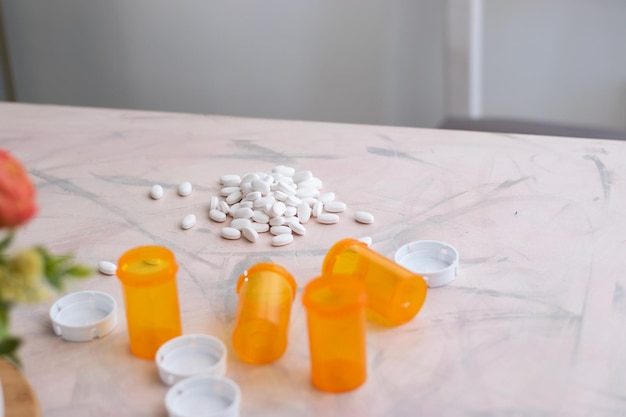 Many white medicine pills over table of room with empty bottles around with copy space