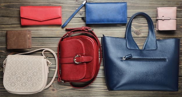 Many women's bags and purses on a wooden background. Top view.