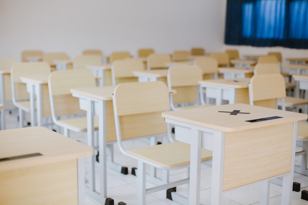 Many wooden tables and chairs well arranged in empty classroom