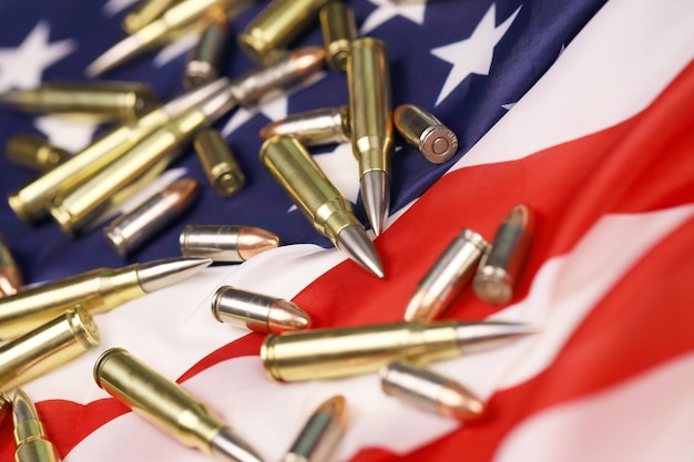 Many yellow 9mm and 556mm bullets and cartridges on United States flag Concept of gun trafficking on USA territory or special ops