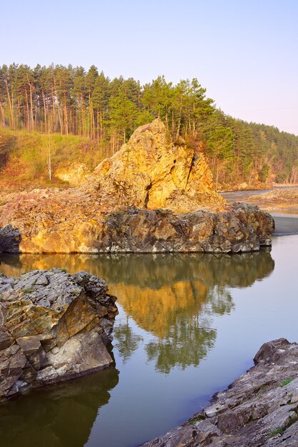 カトゥニ川の岩だらけの土手にあるアルタイ山脈の松の木のマンジェロク急流