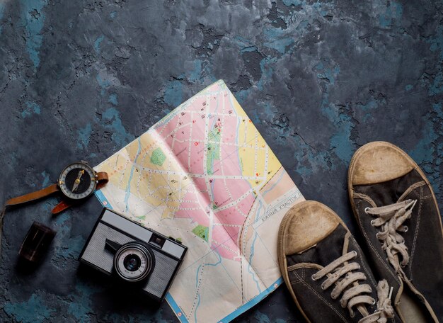 Map compass camera and sneakers on a dark background