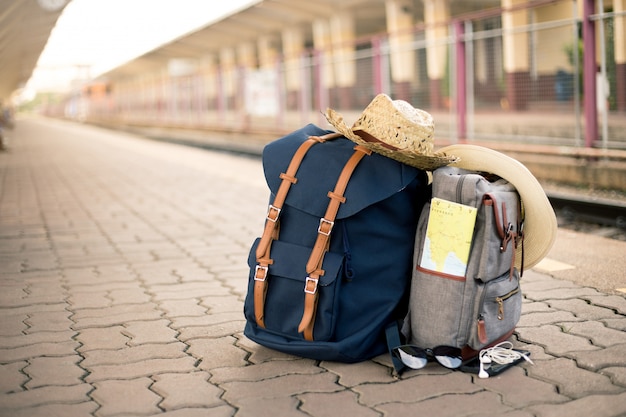 지도는 기차역에서 모자, 선글라스, 휴대 전화 및 헤드폰이 달린 빈티지 가방에 있습니다.