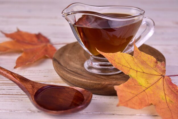 Maple syrup in a glass gravy boat and maple leaves