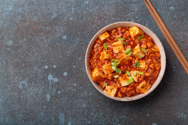 mapo tofu garnished with green onions in bowl top view