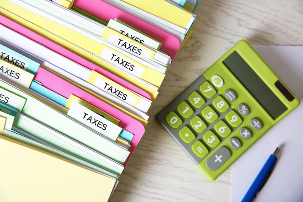 Foto mappen met belastingdocumenten en rekenmachine op witte houten tafel