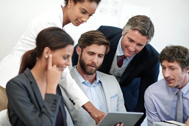 Mapping out their corporate strategy Shot of a group of businesspeople looking at something on a digital tablet