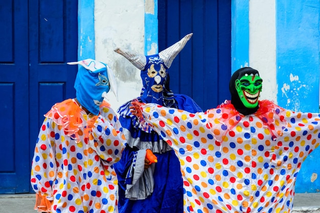 Maragogipe bahia brazil - february 27 2017 three people dressed in colorful costumes and masks at the carnival parade in maragojipe bahia
