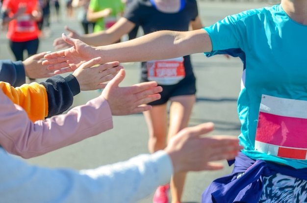 Marathon lopende race, ondersteunende lopers op weg, kinderenhanden die highfive, sportconcept geven