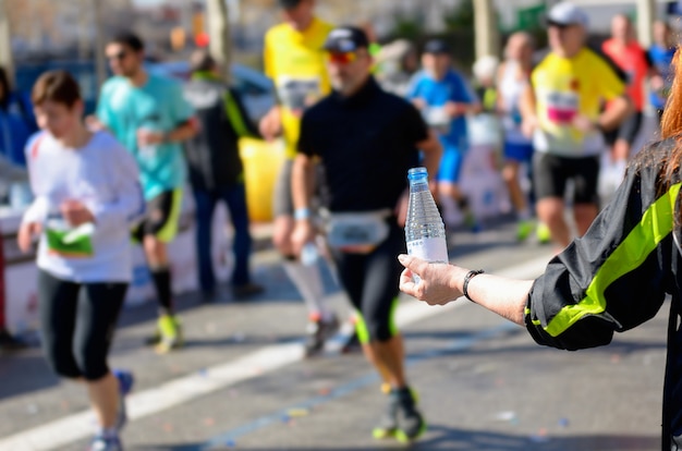 Marathon running race, runners on road, volunteer giving water on refreshment point