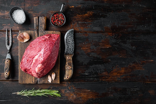 Marble beef raw set, on wooden cutting board with old butcher
cleaver knife, on old dark wooden table, top view flat lay