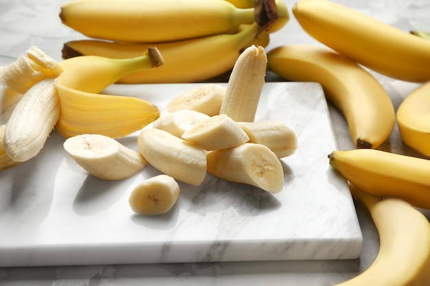 Marble board with sliced bananas on table closeup