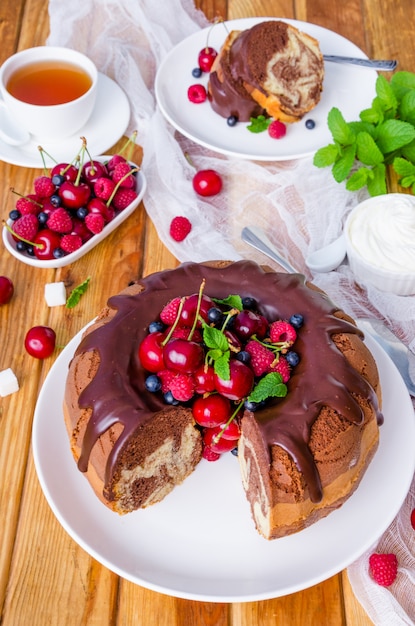 Marble cream cake with chocolate glaze, fresh berries, whipped cream and mint.