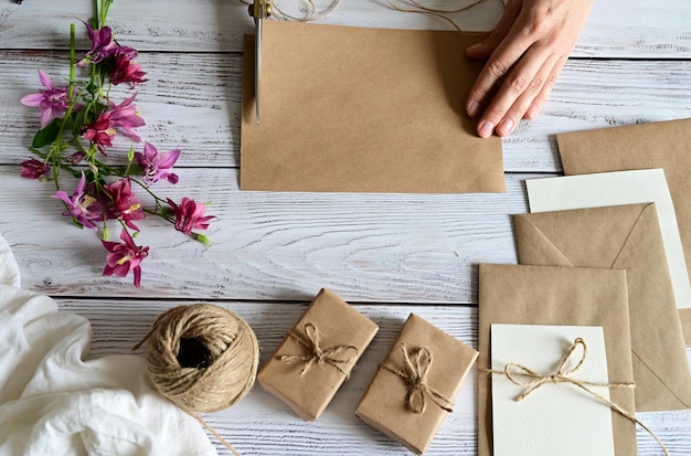 Marble desk with pink and blue flowers postcard kraft envelope twine cotton branch Layout of Women's Day or Mother's Day St Valentine's Day flat position top view