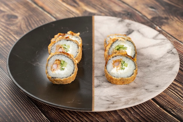 Marble plate of sushi rolls placed on a wooden table.