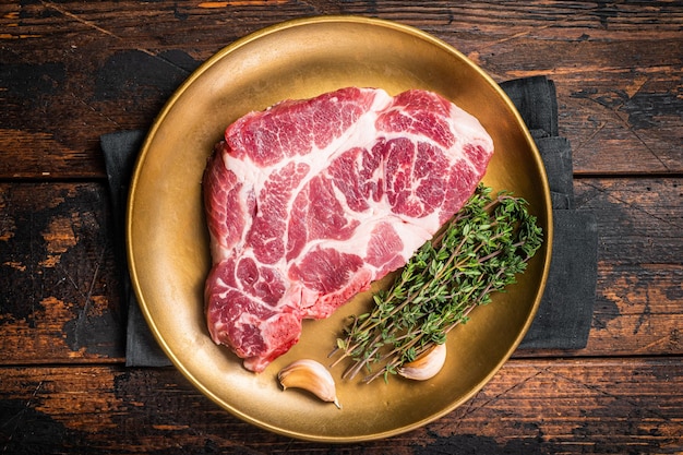 Marble pork steak raw neck meat with thyme Wooden background Top view