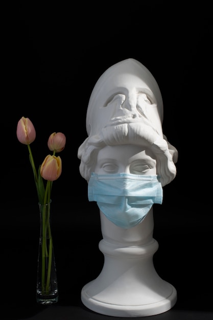 Marble sculpture of historical figure with medical mask and tulips