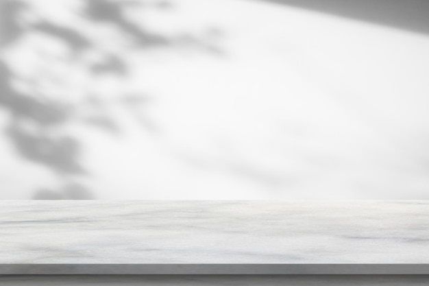 Tavolo in marmo con goccia d'ombra dell'albero su sfondo bianco muro per esposizione di prodotti mockup