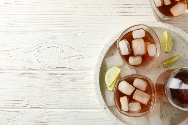 Marble tray with glasses of whiskey and lime on white background, top view