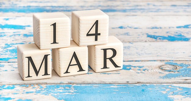 March 14th. Wooden cubes with date of 14 March on old blue wooden background.