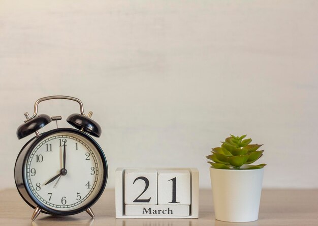 March 21 on a wooden calendar next to the alarm clock.Calendar date, holiday event, or birthday.