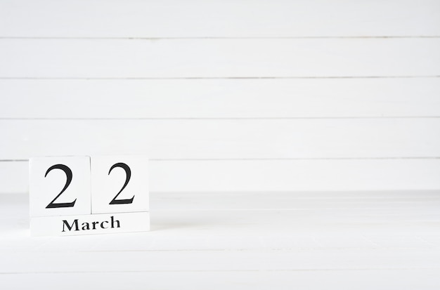 Photo march 22nd, day 22 of month, birthday, anniversary, wooden block calendar on white wooden background with copy space for text.