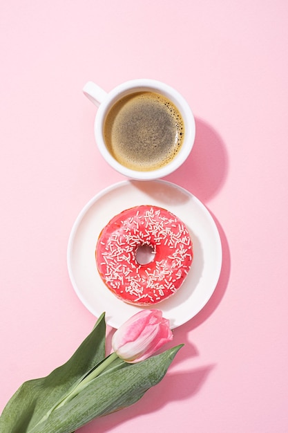 March 8 international women\'s day number eight consisting of a\
cup of coffee and a donut with a pink filling next to pink tulips\
on a pink background space for text