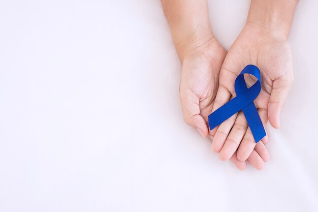 Photo march colorectal cancer awareness month, man holding dark blue ribbon for supporting people living and illness.