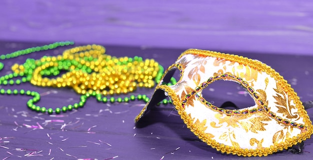 Mardi gras mask e perline su un tavolo di legno. accessori di carnevale madi gras, coriandoli, maschera festiva, veneziana o carnivale. concetto di celebrazione di travestimento.