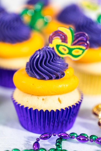 Mardi gras vanilla cupcakes in foil cupcake cups and decorated with italian buttercream frosting