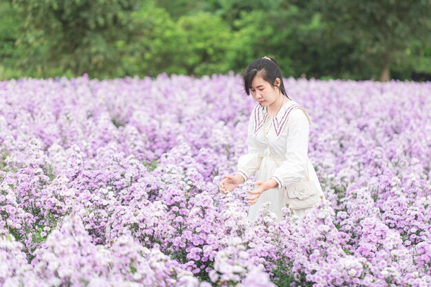 マーガレットの花畑と女性アジアの女性の肖像画が立って、不思議に彼女の休日を楽しんでいます