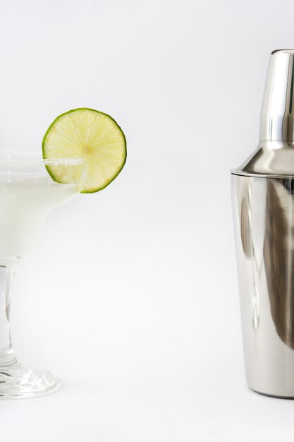 Margarita cocktail and shaker on white surface