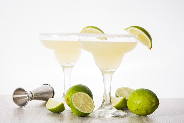 Margarita cocktail with lime in glass on white wooden table