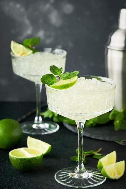 Margarita cocktail with lime tequila mint and ice on dark table with amazing backlight copy space Classic Margarita or Daiquiry Cocktail Bar card or counter concept Selective or soft focus