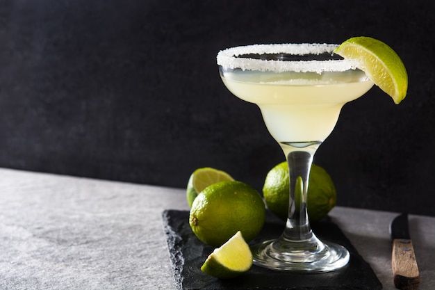 Margarita cocktails with lime in glass on gray stone