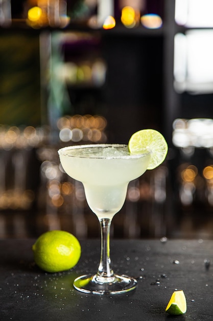 Margarita in a glass with lime in a glass on dark background nuts and greens