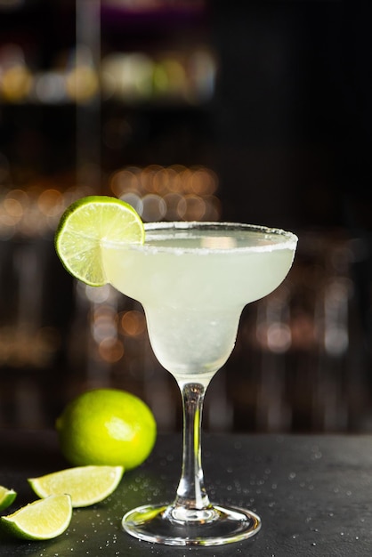 Margarita in a glass with lime in a glass on dark background nuts and greens