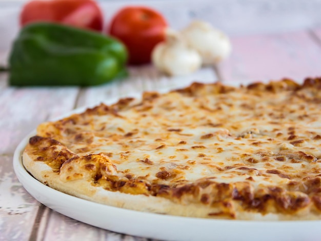 Foto pizza margarita coperta con funghi capsicum, pomodoro e olive servite in un piatto isolato sul tavolo, vista laterale del fast food arabo