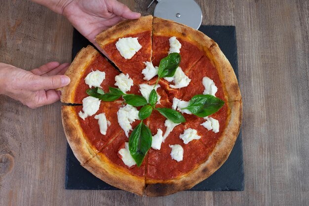 Foto pizza italiana margherita con mozzarella di bufala pomodoro guarnita con basilico fresco su bordo nero