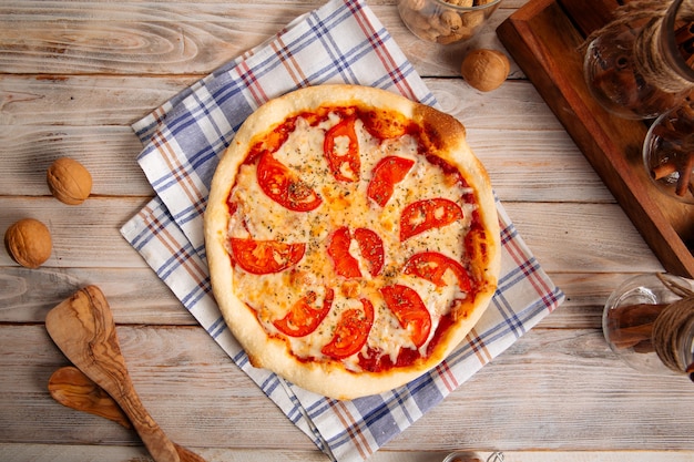 Margherita pizza with tomatoes on the wooden table