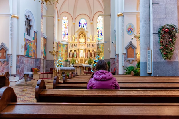 Maribor, Slovenië - 19 januari 2019: Vrouwengebed in de Franciscaanse kerk, interieur in Maribor, Slovenië. Vintage abstract patroon op de achtergrond. Binnen van kathedraal met meisje, vrouwelijke persoon. Binnen