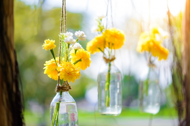 The marigold flowers in a glass bottle hanging