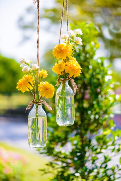 The marigold flowers in a glass bottle hanging