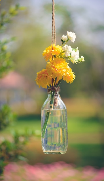 The marigold flowers in a glass bottle hanging