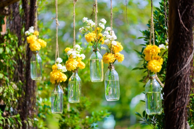 The marigold flowers in a glass bottle hanging