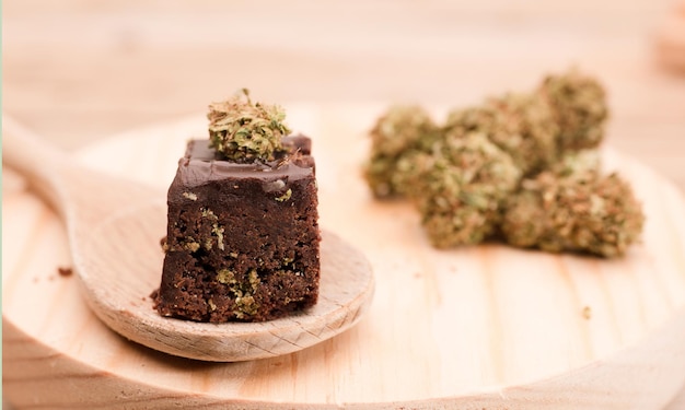 Marijuana cake on a brown wooden tableChocolate cupcake muffins with cannabis buds