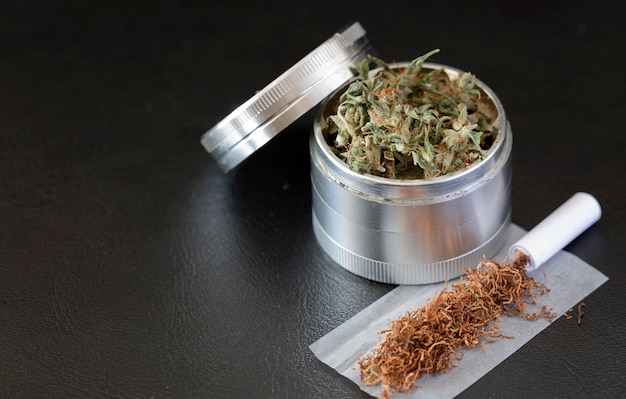 Photo marijuana on grinder with cigar dark background