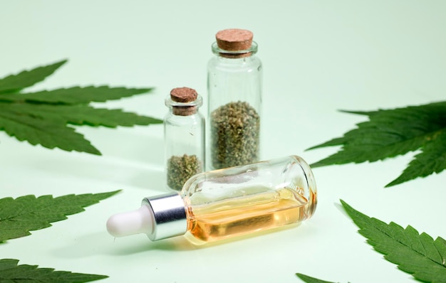 marijuana oil in drops dispenser bottle with buds and leaves green background