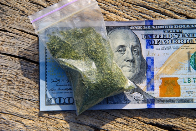 Photo marijuana in packet and 100 dollar bill on the wooden table